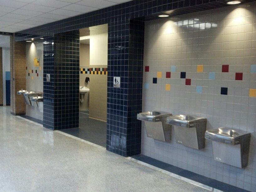 Completed public restroom corridor with tiled walls and drinking fountains