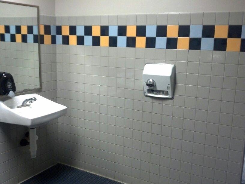 Completed tiled restroom interior with sink and decorative tile band